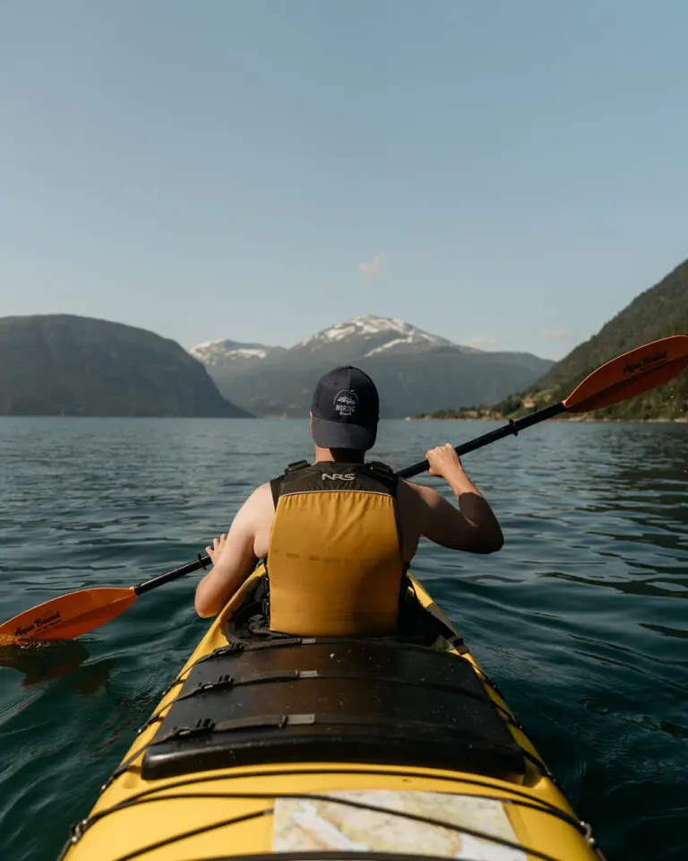 Man kayaking in front of the mountains in Norway